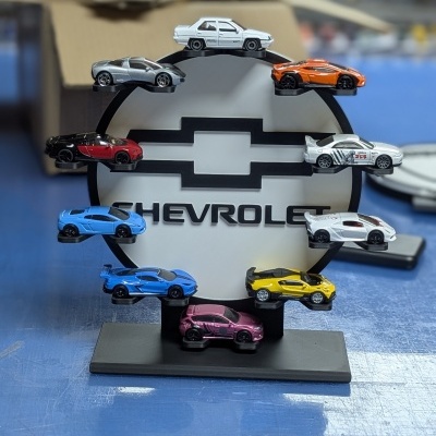 Expositor preto com placa branca CHEVROLET e miniaturas de carros coloridos
