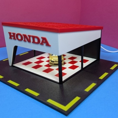 Miniatura de garagem Honda com carro dourado e chão de azulejos vermelhos e brancos