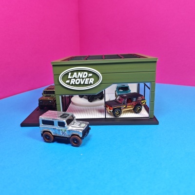 Mini expositor verde Land Rover com carros de brinquedo coloridos em redor