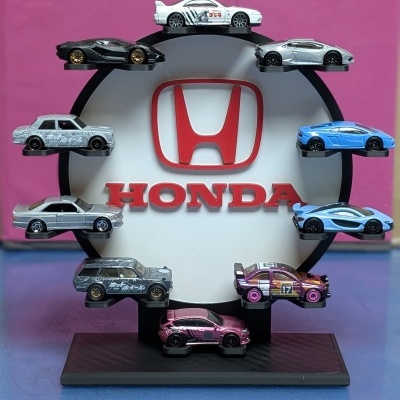 Expositor preto com miniaturas de carros e logótipo Honda vermelho no centro