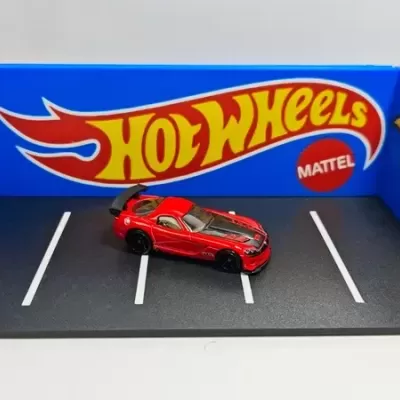 Miniatura de carro Hot Wheels vermelho em base de exposição com texto e painéis azuis
