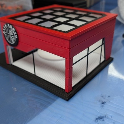 Maquete de edifício comercial vermelho com janelas transparentes e logótipo Alfa Romeo