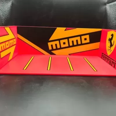 Base vermelha com decoração momo e símbolo Ferrari em amarelo e preto