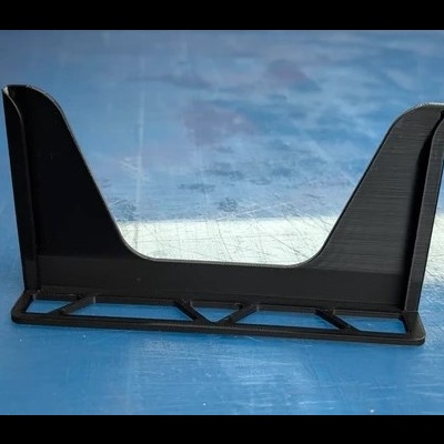 Suporte preto de plástico com base retangular e duas extremidades verticais altas sobre superfície azul.