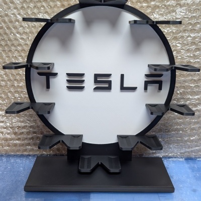 Suporte redondo preto e branco com texto Tesla e prateleiras em fundo de plástico bolha