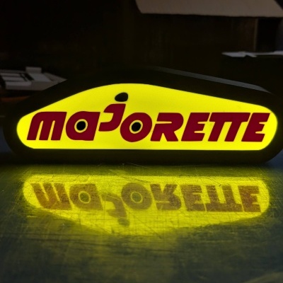 Sinal luminoso amarelo com texto MAJORETTE em vermelho