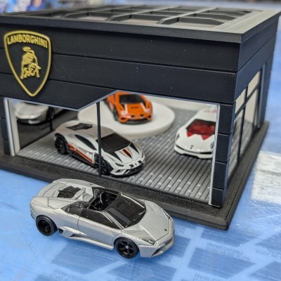 Miniaturas de carros Lamborghini e estande preto com logótipo dourado