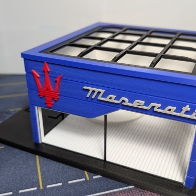 Miniatura loja Maserati azul com logotipo vermelho e texto prateado