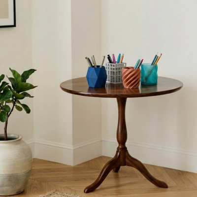 Mesa redonda de madeira com porta-canetas coloridos e planta ao lado