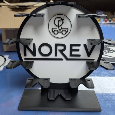 Suporte de exposição circular preto e branco com texto NOREV e plataformas para objetos