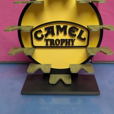 Suporte amarelo e preto com texto CAMEL TROPHY e várias plataformas verdes