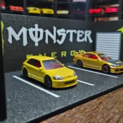 Miniaturas de carros amarelos em parque de estacionamento em miniatura com decoração MONSTER ENERGY