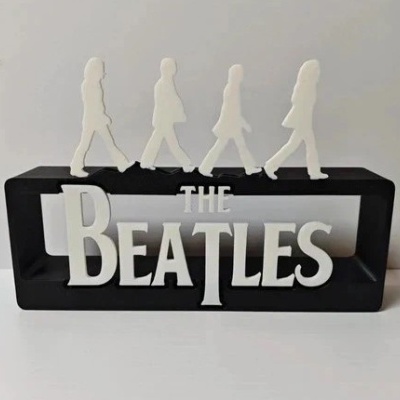 Escultura das letras THE BEATLES e figuras dos membros da banda numa base preta.