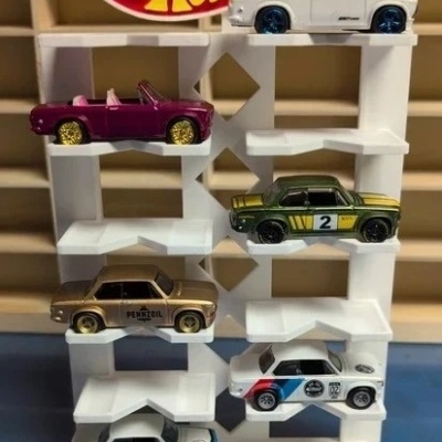 Suporte branco com seis carrinhos Hot Wheels coloridos e logo Hot Wheels ao fundo
