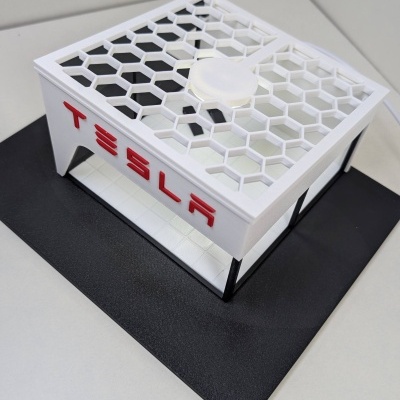 Modelo de edifício com letras TESLA em branco e vermelho sobre base preta