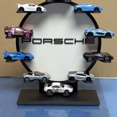 Miniaturas de carros desportivos coloridos numa exposição com círculo branco e texto PORSCHE