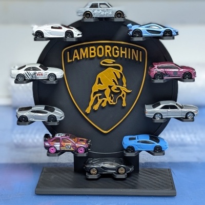 Doze carrinhos de brinquedo em miniatura numa base preta com logo Lamborghini