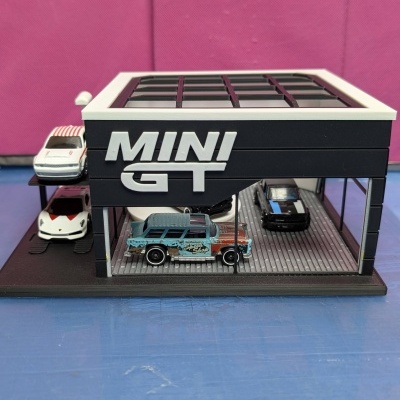 Miniatura de garagem com carros em miniatura e inscrição MINI GT