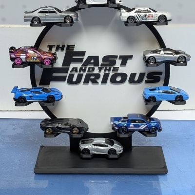 Miniaturas de carros desportivos em suporte circular com o texto THE FAST AND THE FURIOUS ao fundo