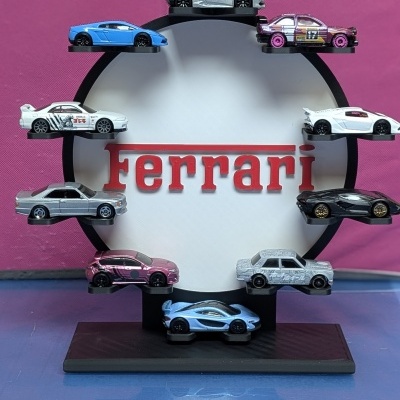 Exposição circular com carros de brinquedo coloridos em torno do texto Ferrari