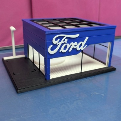 Modelo arquitetónico miniatura de loja Ford azul com texto branco e base preta