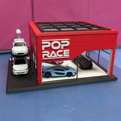Maqueta de garagem vermelha com carros em miniatura e texto POP RACE