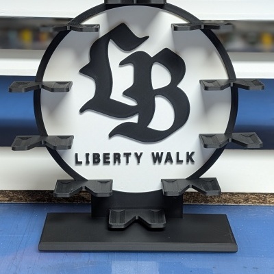 Expositor com logo LB e texto LIBERTY WALK, preto e branco, sobre superfície azul