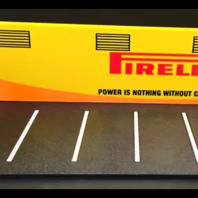 Miniatura de box de corridas Pirelli com paredes amarelas, chão preto e logos Pirelli