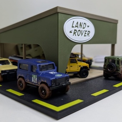 Diorama com carros Land Rover miniatura em exposição com tecto verde e logótipo