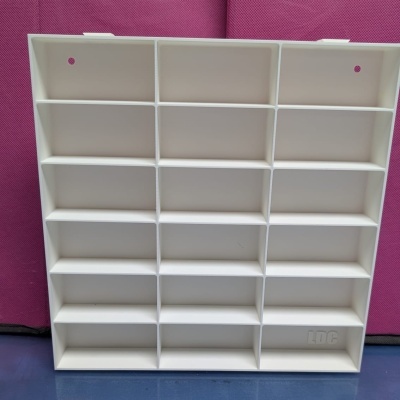 Estante branca com 20 compartimentos quadrados, fundo rosa e azul.