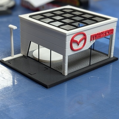 Miniatura de edifício com logo Mazda em branco e vermelho
