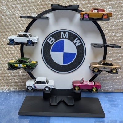 Suporte preto para carros miniatura com logótipo BMW ao centro e seis carros de coleção coloridos expostos