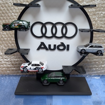 Expositor circular preto com miniaturas de carros e logótipo Audi em fundo branco