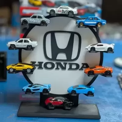 Suporte circular preto com logótipo Honda e miniaturas de carros coloridos à volta.
