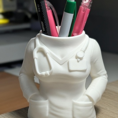 Suporte de canetas branco em formato de uniforme médico com canetas de várias cores.