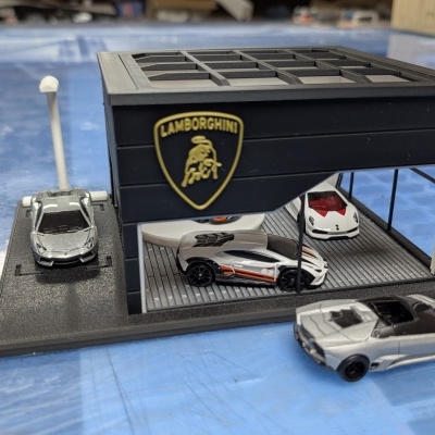 Miniatura garagem Lamborghini preta com quatro carros desportivos em miniatura.