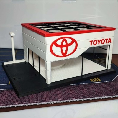Miniatura de edifício Toyota branco com detalhes vermelhos e janelas pretas