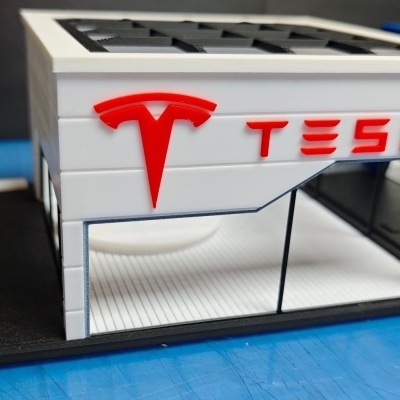 Miniatura de loja Tesla em plástico com logo vermelho e texto TESLA
