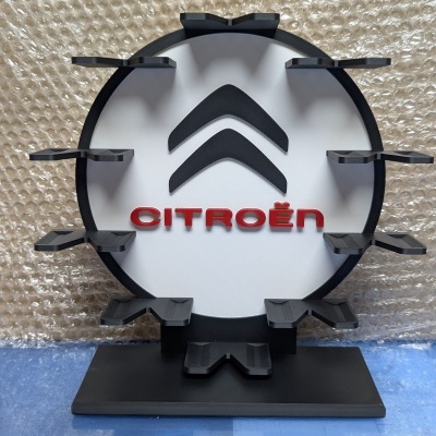 Expositor redondo preto e branco com logótipo da Citroën em vermelho sobre fundo de plástico bolha.