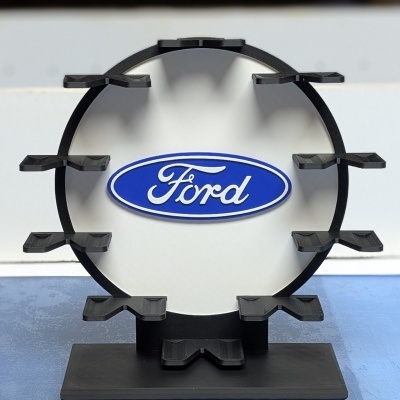 Suporte preto circular com logótipo Ford azul e branco no centro
