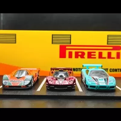 Miniaturas de carros de corrida num estacionamento de brinquedo com fundo amarelo e logo PIRELLI
