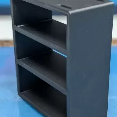 Prateleira preta plástica com três níveis sobre superfície azul