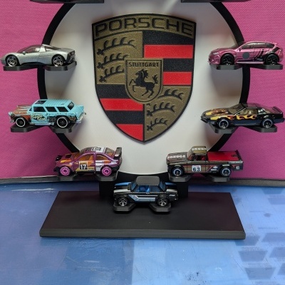 Carros de brinquedo expostos em suporte com logotipo Porsche