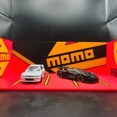 Miniaturas de carros branco e preto junto a logos MOMO e Ferrari