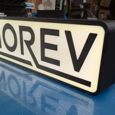 Letreiro luminoso com texto NOREV em preto sobre fundo branco