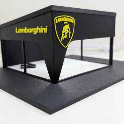 Modelo em miniatura de edifício preto com logótipo e nome Lamborghini em amarelo numa base preta