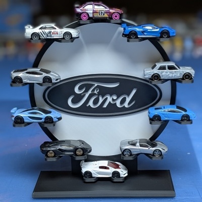 Expositor circular preto e branco com logo Ford e miniaturas de carros coloridos