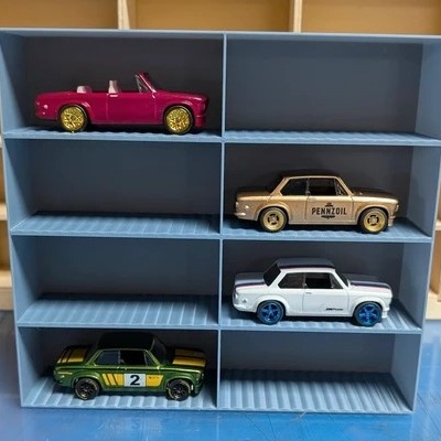 Quatro carros em miniatura em prateleira azul e fundo de madeira.