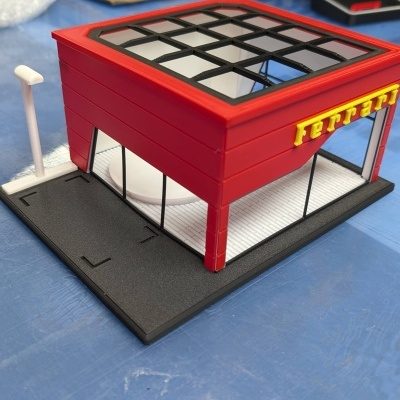 Miniatura de prédio vermelho com placa Ferrari e base preta e branca