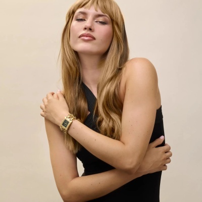 Mulher com vestido preto e relógio dourado no pulso esquerdo